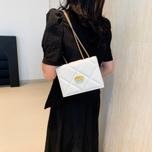 Elegant white quilted crossbody bag with gold chain strap and metal clasp on black dress