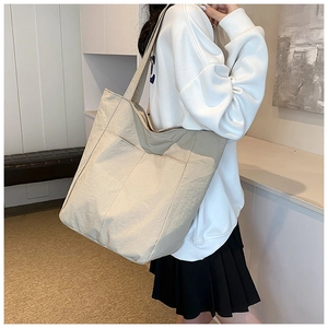 Detail of minimalist cream tote bag with pleated texture and wide shoulder strap