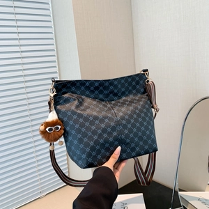 Vintage pattern bucket bag with striped wide strap and monster plush charm in lifestyle setting