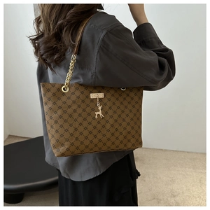 Close-up of deep brown quilted tote bag with golden deer charm and chain strap detail