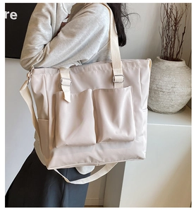 Detail of beige Oxford tote bag with dual front pockets and adjustable silver buckles