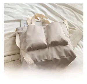 Detail of beige nylon tote bag with functional front pockets and adjustable strap