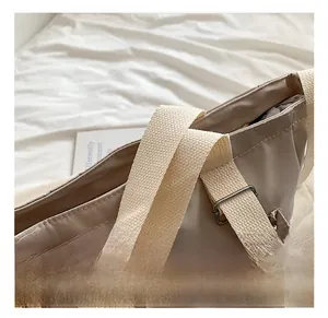 Detail of the wide woven strap and metal buckle on the khaki tote shoulder bag
