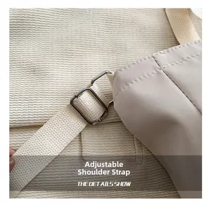 Close-up of adjustable shoulder strap with silver metal buckle on a beige tote bag