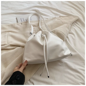 Detail of white bucket bag with glossy synthetic leather and silver metal ring hardware