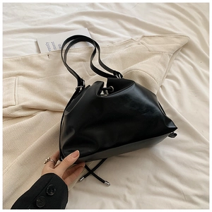 Detail of black PU leather bucket bag with drawstring closure and silver hardware accents