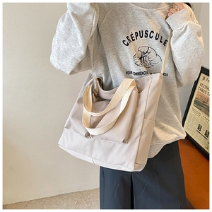 Detail of beige nylon tote bag with wide handles and crossbody strap for daily commute