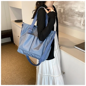 Detail of navy blue nylon tote bag with multiple front pockets and woven straps