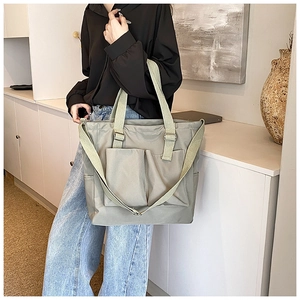 Detail of grey-green nylon tote bag with dual front pockets and adjustable strap