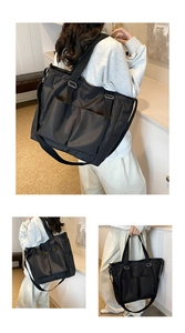 Detail of black nylon tote bag featuring front dual pockets and adjustable shoulder straps