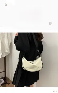 Side view of cream moon bag with black trim and adjustable wide strap on model