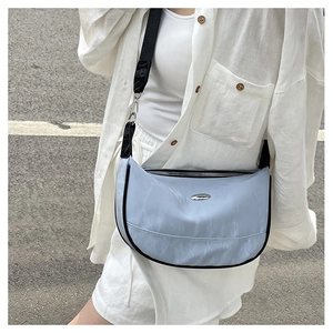 Detail of light blue crescent bag showing the woven fabric texture and silver logo plate