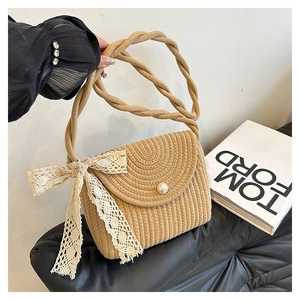 Detail of straw woven bag featuring a pearl clasp and delicate white lace floral bow