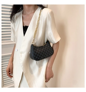 Detail of a small crescent hobo bag with vintage geometric patterns and a gold chain strap