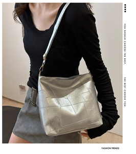 Detailansicht der silbernen Metallic-Patchwork-Tasche mit goldenen Beschlägen an einem Model