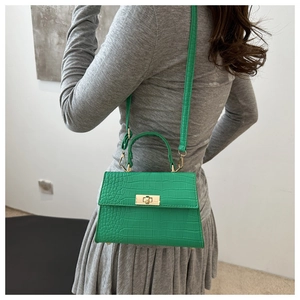Side view of a bright green crocodile texture mini bag styled with a grey dress