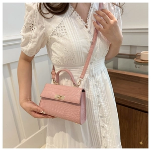 Pink crocodile pattern handbag with gold clasp detail worn with white dress