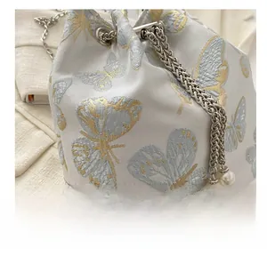 Close-up of jacquard bucket bag with butterfly embroidery and pearl chain detail