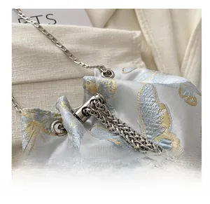 Close-up of butterfly embroidery and silver chain on light blue satin bucket bag