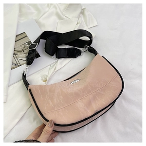 Detail of pink crescent bag showing glossy wrinkled texture and black strap accents