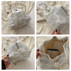 Detail view of silk embroidery bucket bag with butterfly pattern and pearl chain strap