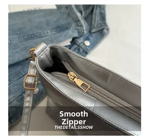 Detail showing smooth gold zipper and pebble texture on silver crossbody handbag
