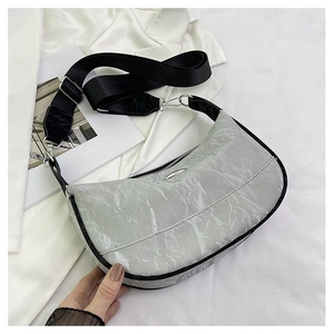 Detail of silver crescent moon bag featuring glossy wrinkled texture and wide black strap