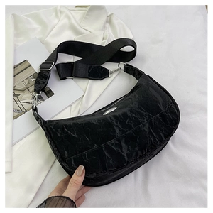 Detail of black pleated half-moon crossbody bag with wide strap and silver hardware