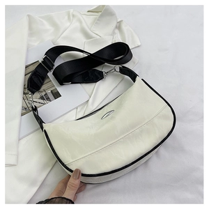 Detail of off-white hobo bag with black trim, wide shoulder strap and metal buckle
