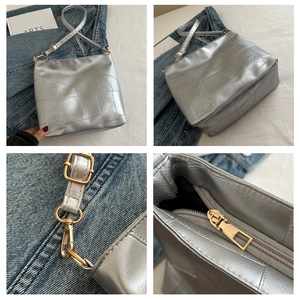 Detail view of silver textured shoulder bag showing stitch patterns and gold hardware