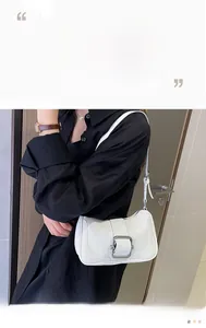 Detail of white leather underarm bag with large silver metal buckle and thin shoulder strap