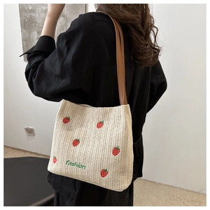 Beige woven straw tote bag with strawberry embroidery and brown shoulder straps