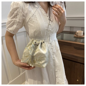 Detail of silk-texture drawstring bucket bag with blue bamboo embroidery and pearls