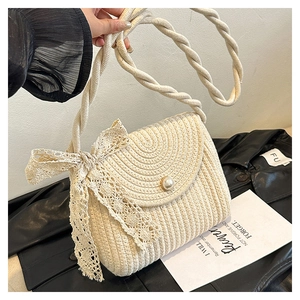 Detail of hand-woven straw bag with a lace bow, pearl button, and textured cream fabric
