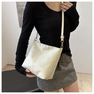 Detail of beige quilted faux leather handbag with adjustable strap and gold metal hooks
