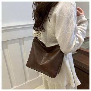 Detail der dunkelbraunen Karo-Tasche mit Vintage-Ledertextur und seitlicher Metallschnalle