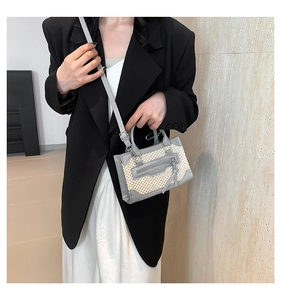 Détail du sac bandoulière en cuir gris et paille beige sur modèle avec bandoulière