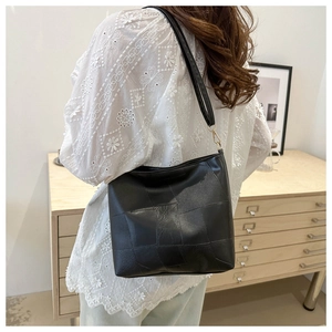 Minimalist black leather woven tote bag with gold hardware for women, lifestyle view