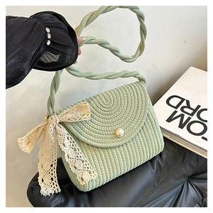 Close-up of light green woven bag with large lace bow and elegant pearl magnetic clasp