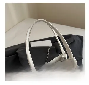 Detail of white leather handbag handle with decorative silver bead chain on blazer