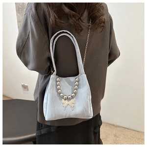 Close-up of light blue pleated bucket bag featuring silver bead chain and butterfly charm