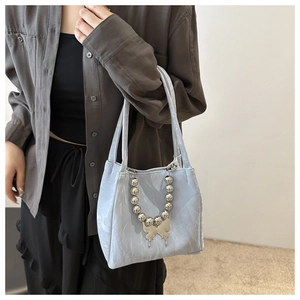 Detail of light blue pleated faux leather bag with silver butterfly and bead chain strap