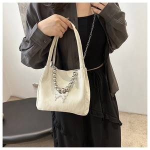 Detail of white jacquard fabric bucket bag with silver bead chain and butterfly charm
