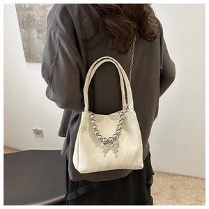Detail of cream white handbag with chunky silver chain and butterfly pendant detail