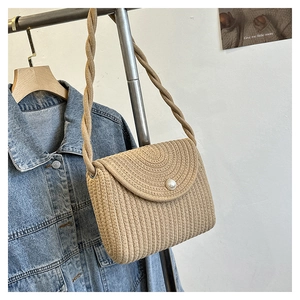 Detail of beige woven straw shoulder bag featuring a pearl clasp and rope strap