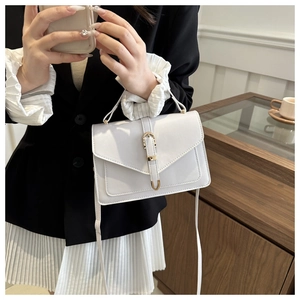 Détail du sac blanc avec rabat en V, boucle dorée et poignée porté par un mannequin