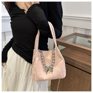 Pink bucket bag with butterfly charm and silver bead chain shown on a model's shoulder