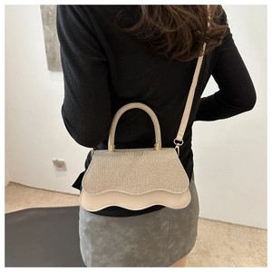 Detail of elegant cream handbag with glitter texture flap and wavy scalloped edge