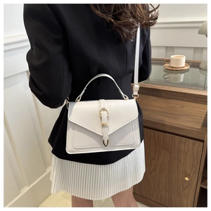 Vue de côté du sac à bandoulière blanc avec boucle dorée sur un mannequin dans un salon