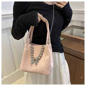 Detail of pink fabric tote bag with silver butterfly charm and chunky bead chain decoration